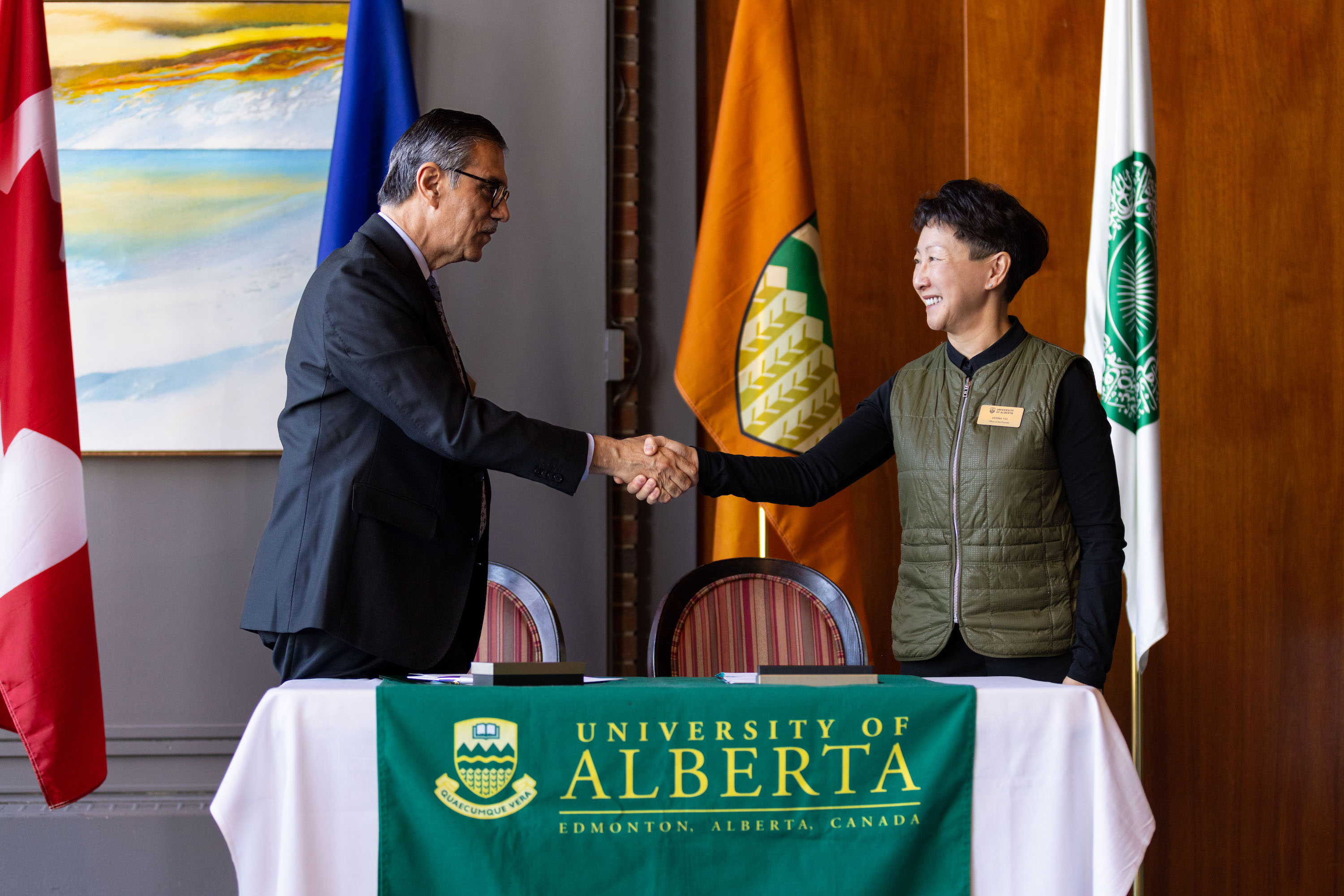 dr. Shahabuddin and dr. Yiu shake hands in front of U of A flags