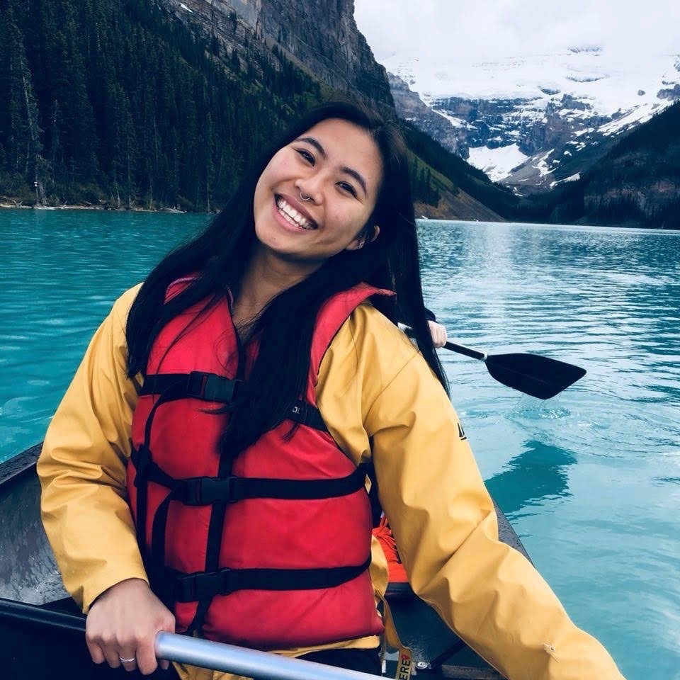 young woman in boat on mountain lake smiling into camera