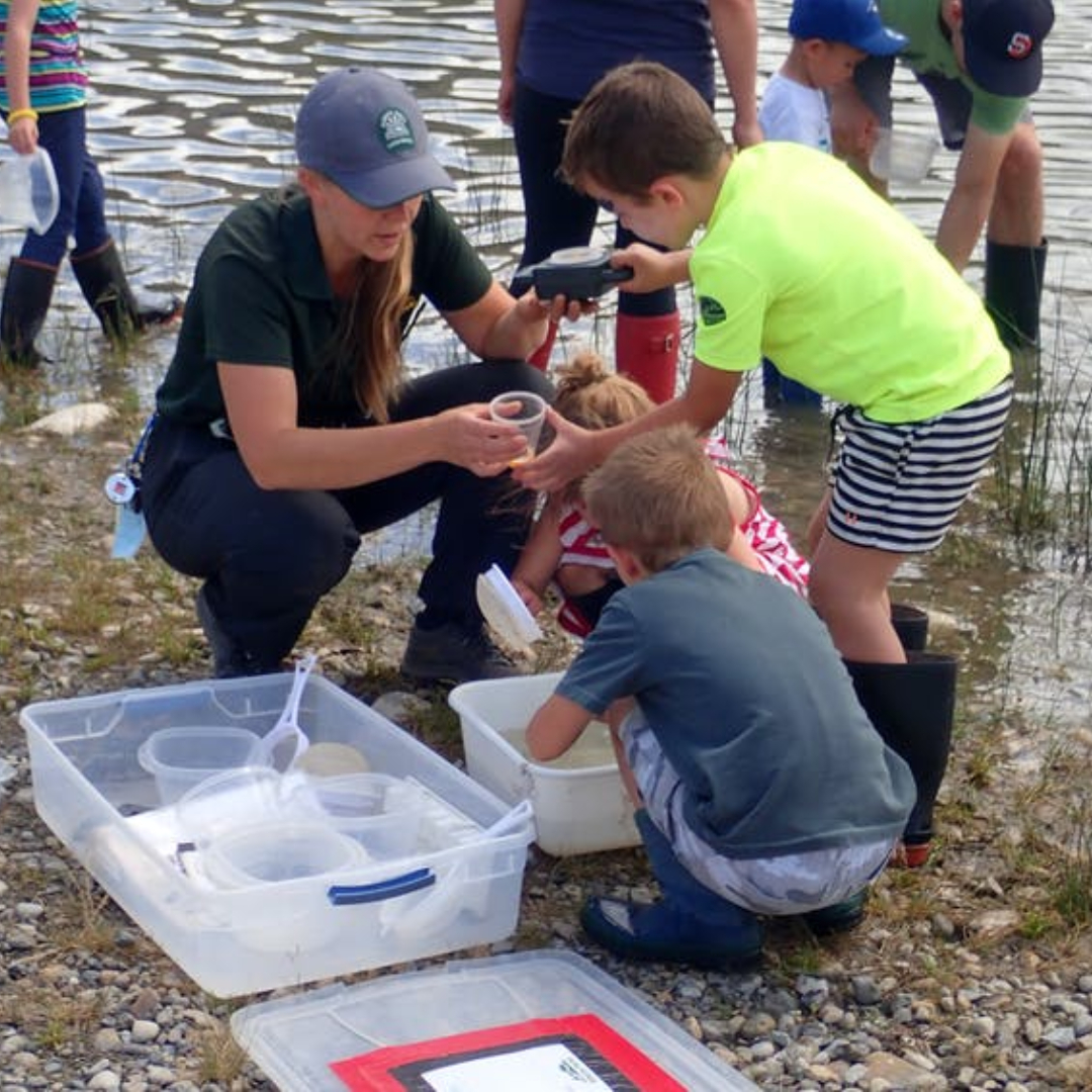 park ranger teaching youth about lakes and water by taking water samples during an Alberta parks interpretation lesson