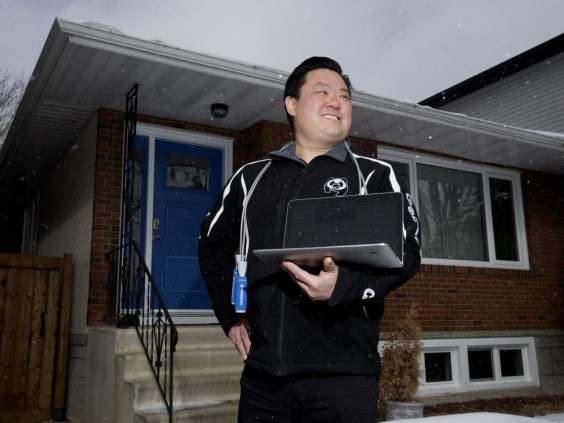 Professor Loren Chiu stands outside house with laptop in hand