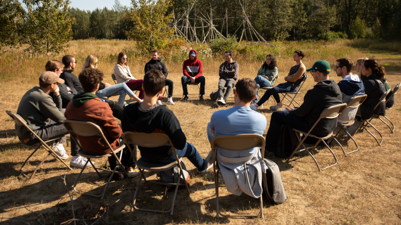 Students sit in a circle as they participate in an experiential learning exercise
