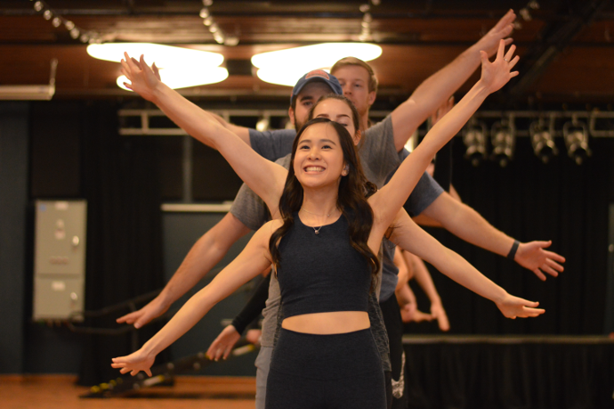 Law Show students perform on stage with hands and arms outstretched.