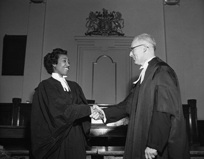 Violet King shakes hands with E J McCormick with whom she articled. (June 1954)