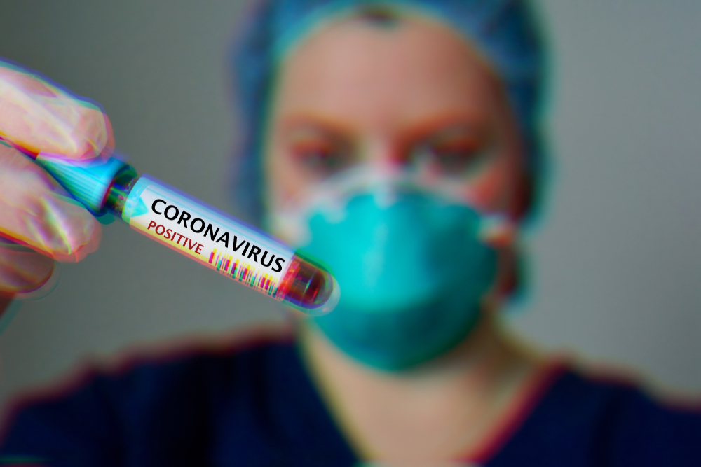 A female scientist holding a vial labeled with Coronavirus.