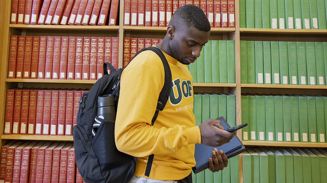 Student in the library looks at a smartphone