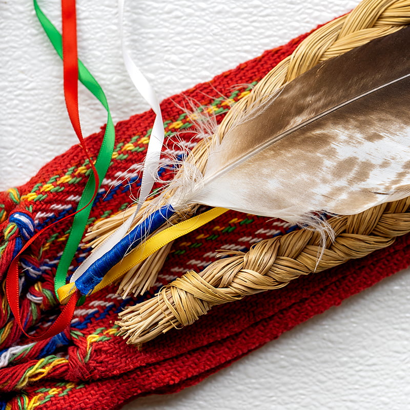 An eagle feather, sweetgrass and Metis sash.