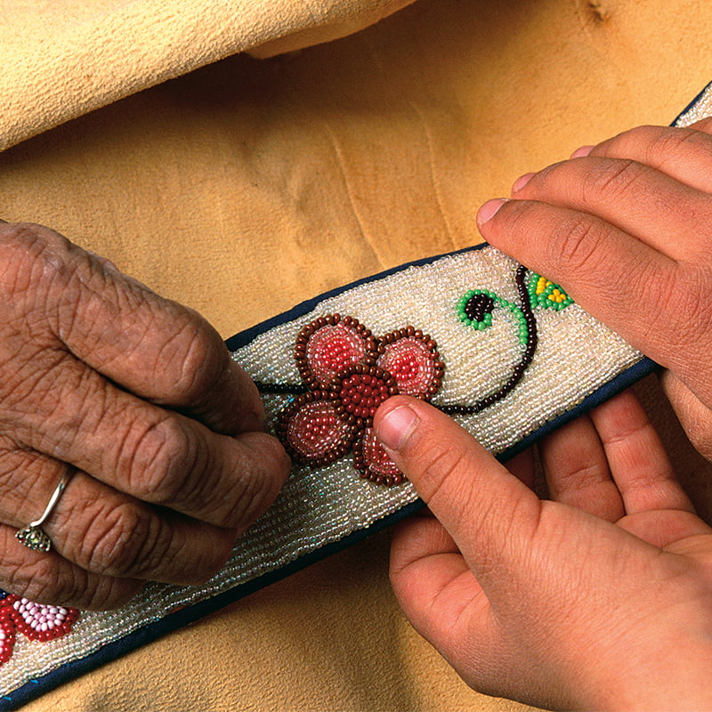 Close up of hands holding a beaded sash