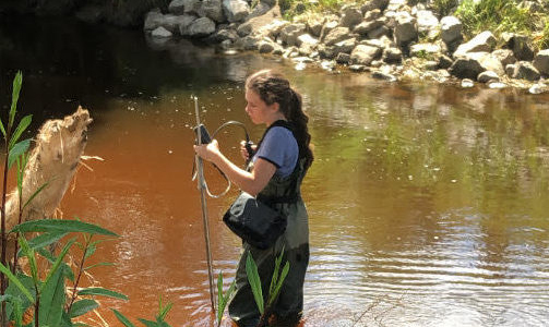 Student conducting research at a river site