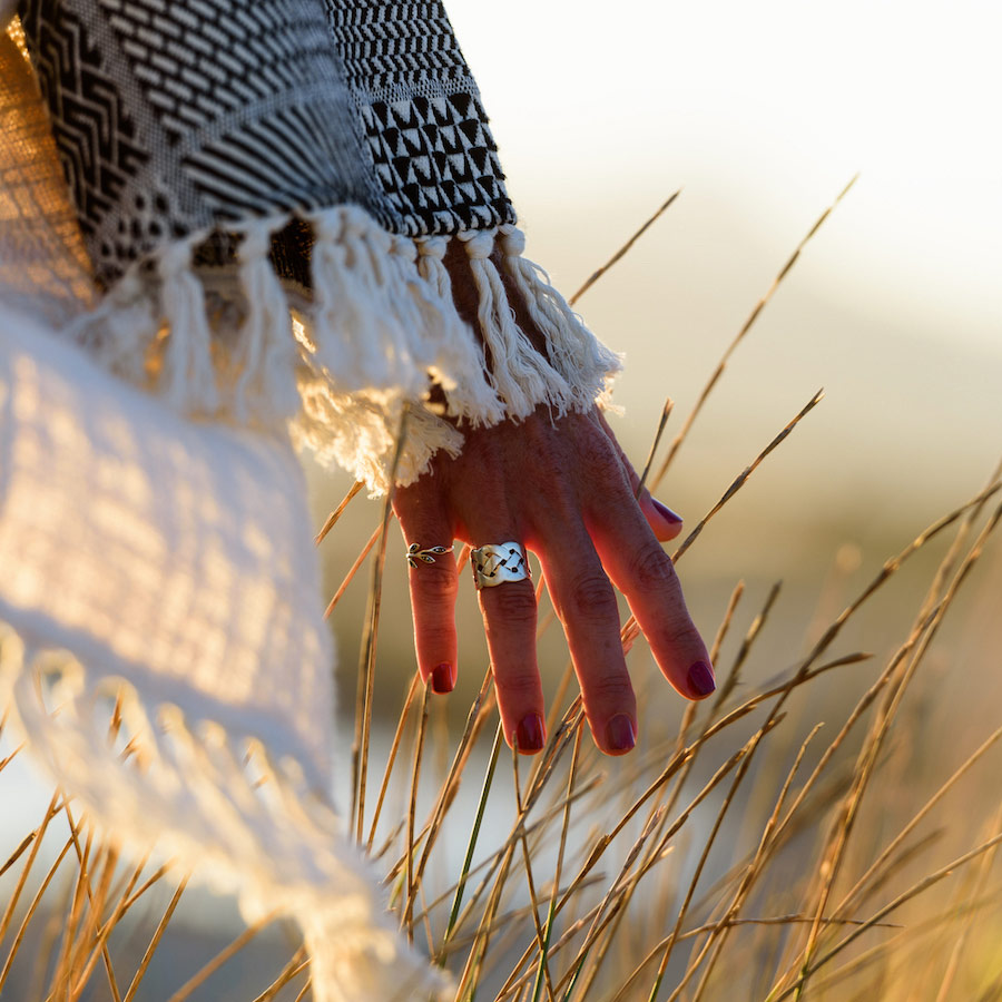 Hand with rings on two fingers running through tall grass
