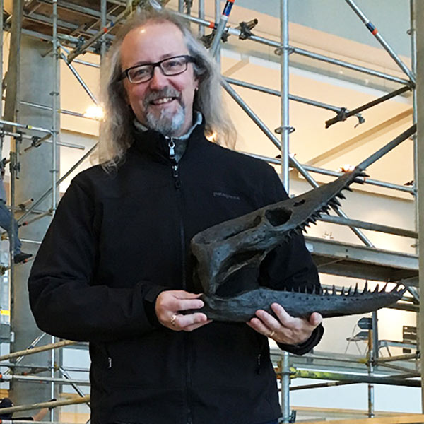 Profile photo of Michael Caldwell holding a dinosaur skull