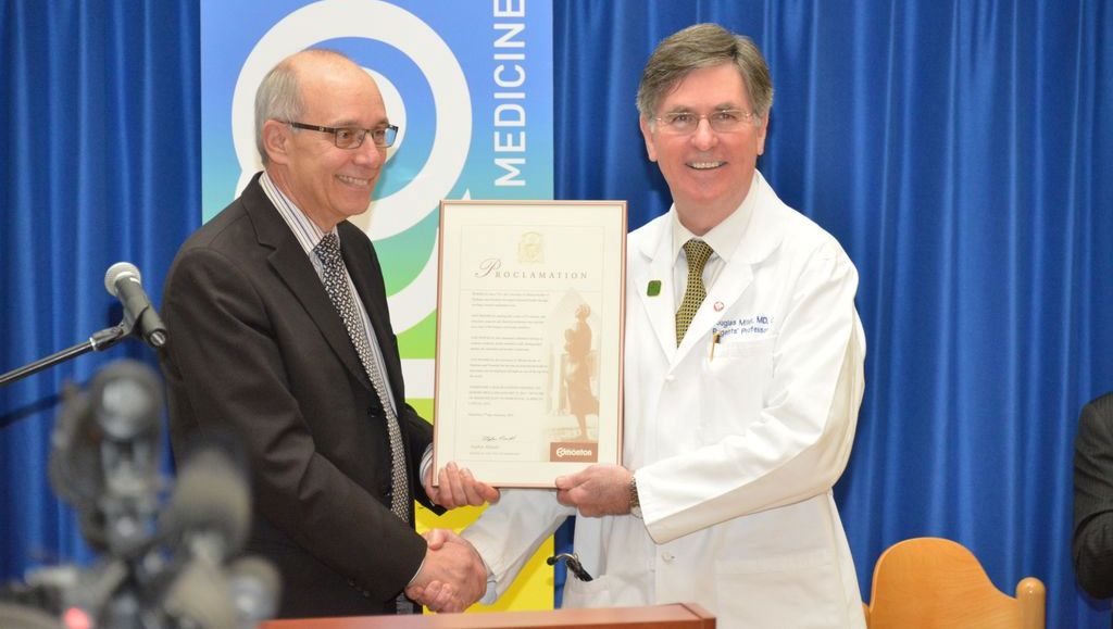 Mayor Stephen Mandel and Dr. D Douglas Miller holding a proclomation commemorating January 17, 2013, as 100 Years of Medicine Day in Edmonton