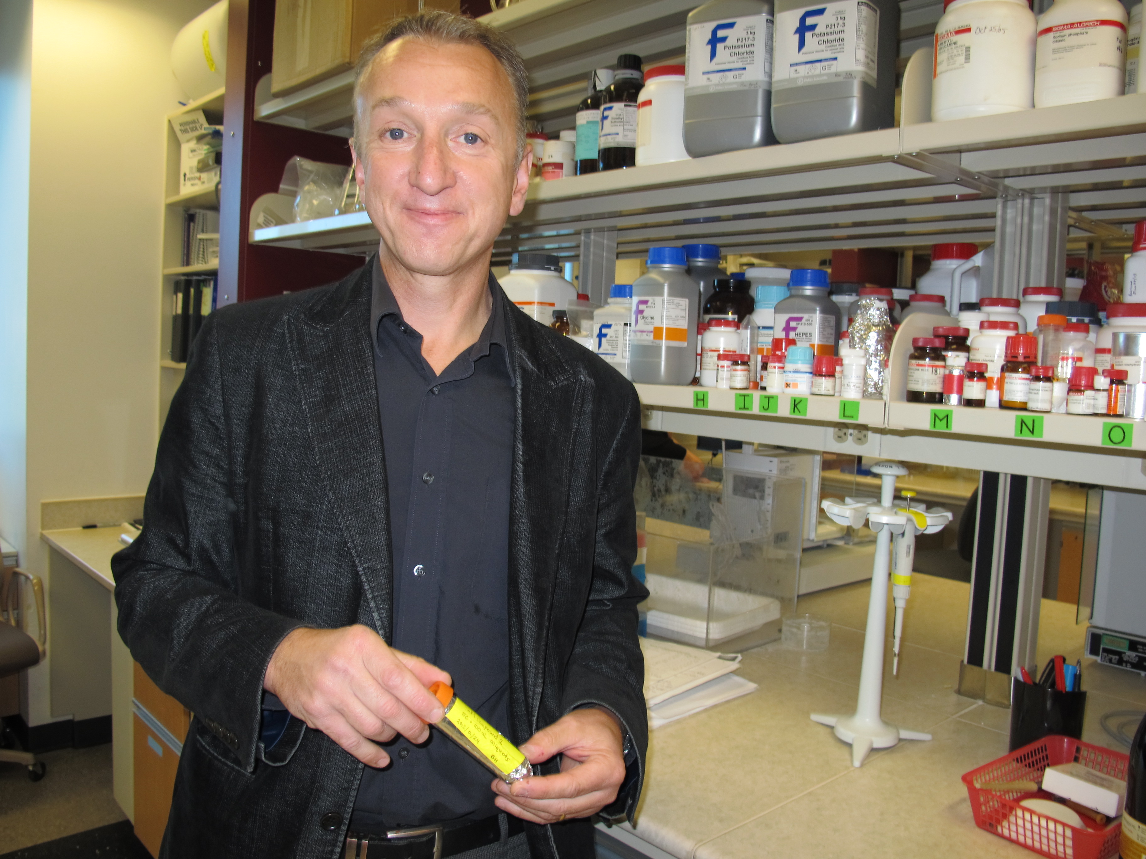 Dr. Light holding the resveratrol-based drug compound in his research lab 