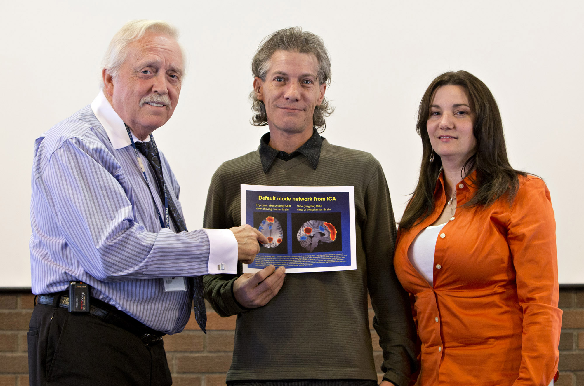 Research psychiatrist Tim Gillese, study participant Kirk Haakensen, and Henwood Treatment Centre Clinical Supervisor Jasmine Fulks with an MRI image of a brain scan used to tailor treatment for alcoholism.