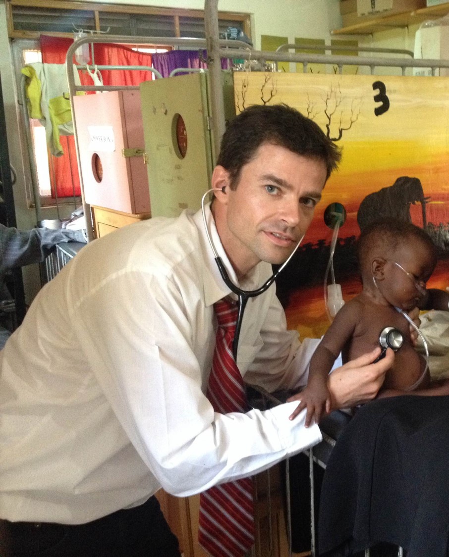 Michael Hawkes helping a child in Uganda.