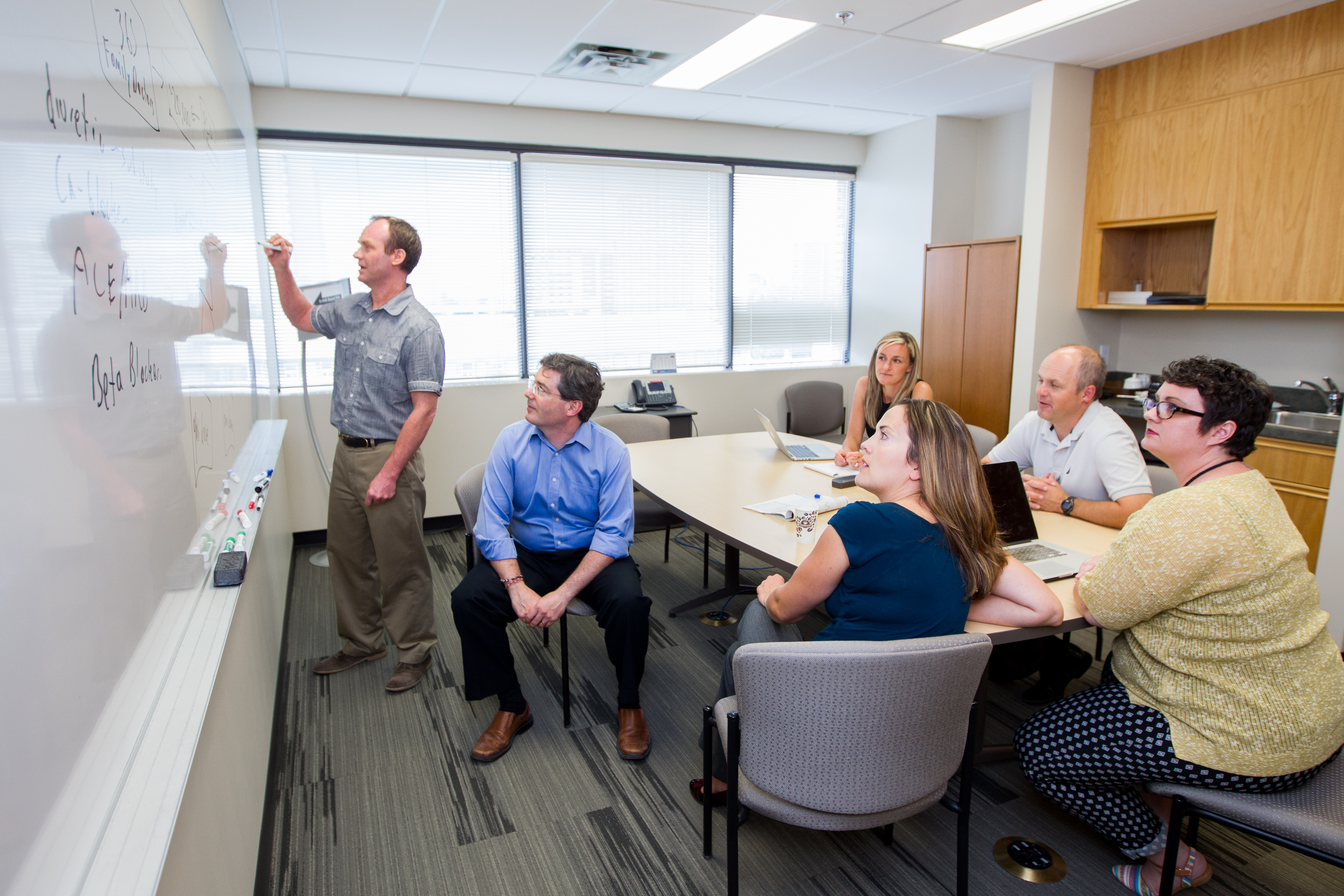 Michael Allan (left) leads a discussion with his team which includes Scott Garrison, Adrienne Lindblad, Tina Korownyk, Michael Kolber, and Sharon Nickel. Colleague James McCormack is absent.