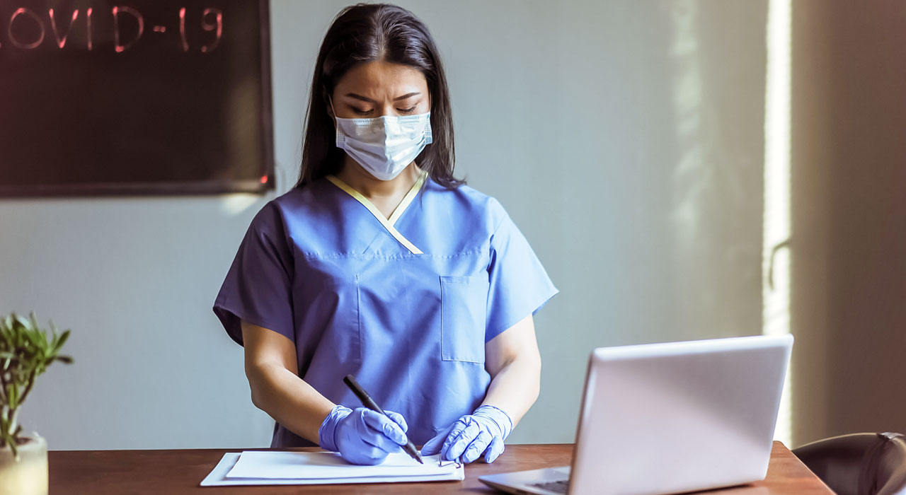 Medical resident writes while wearing a protective mask