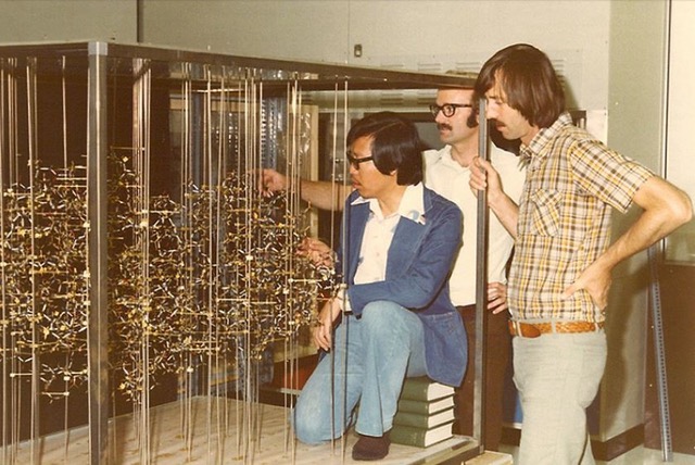 Michael James and researchers standing in front of a structure demonstrating Streptomyces Griseus Peptidase B (SGPB)