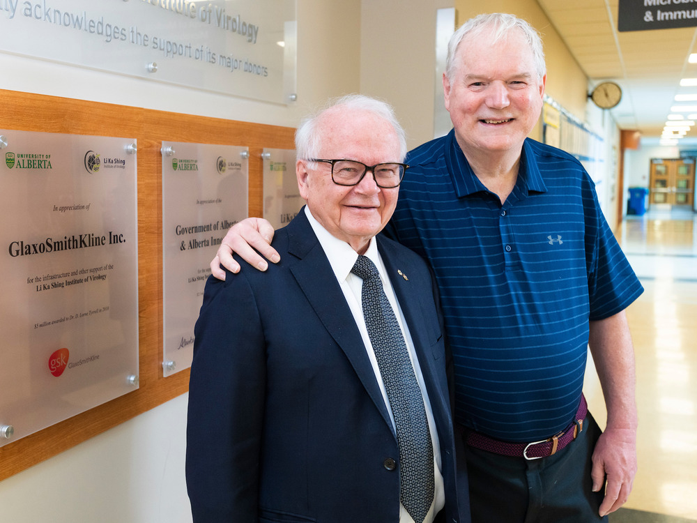 D. Lorne Tyrrell (left) and Michael Houghton posing together in a hallway in the Li Ka Shing Centre for Health Research Innovation.