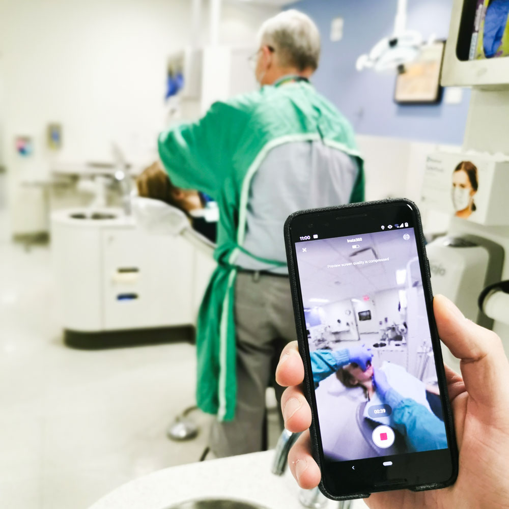 Phone being used to film a dentist working on a patient
