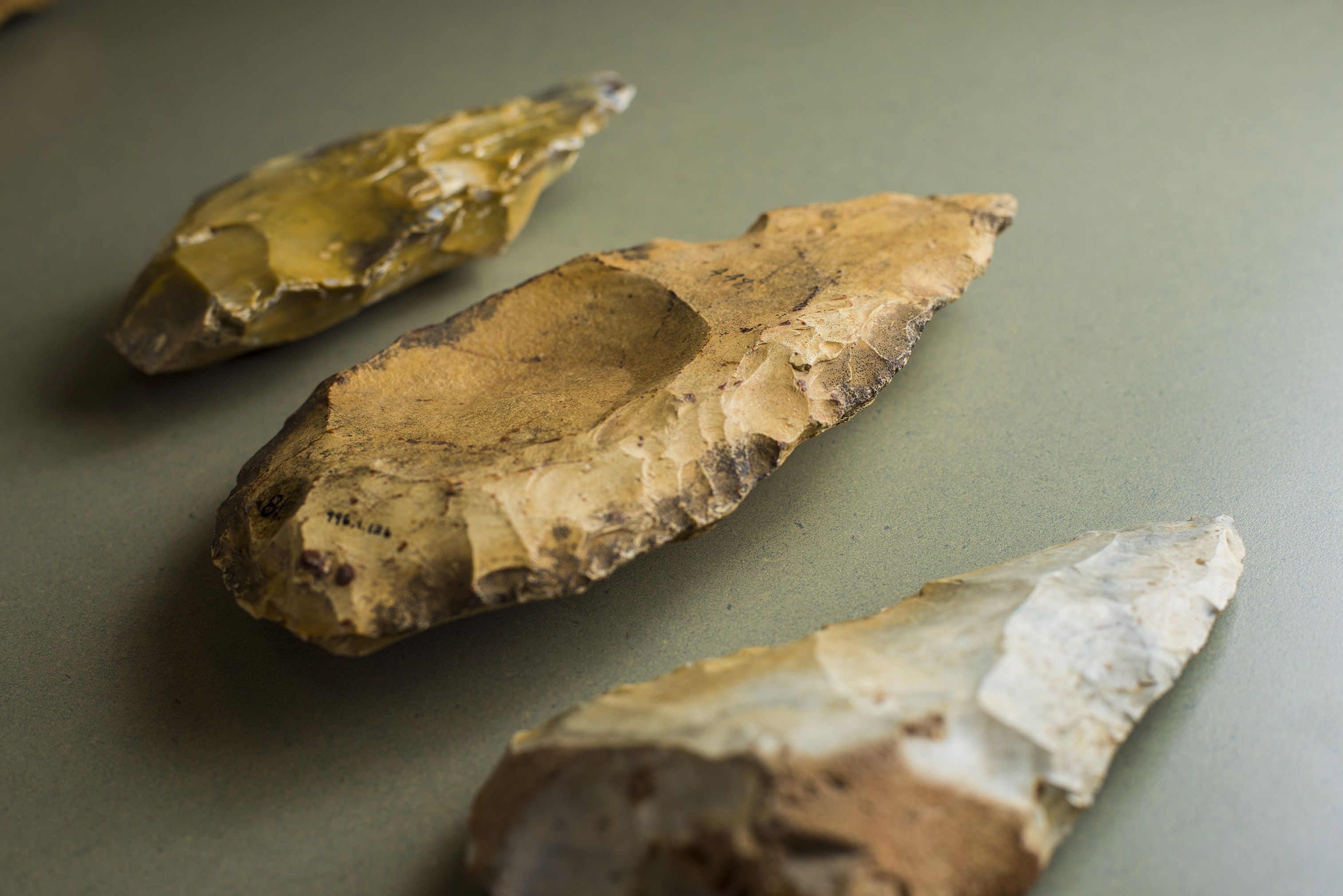 Three chiselled arrow-head shaped stone tools with a rounded, indented center depression