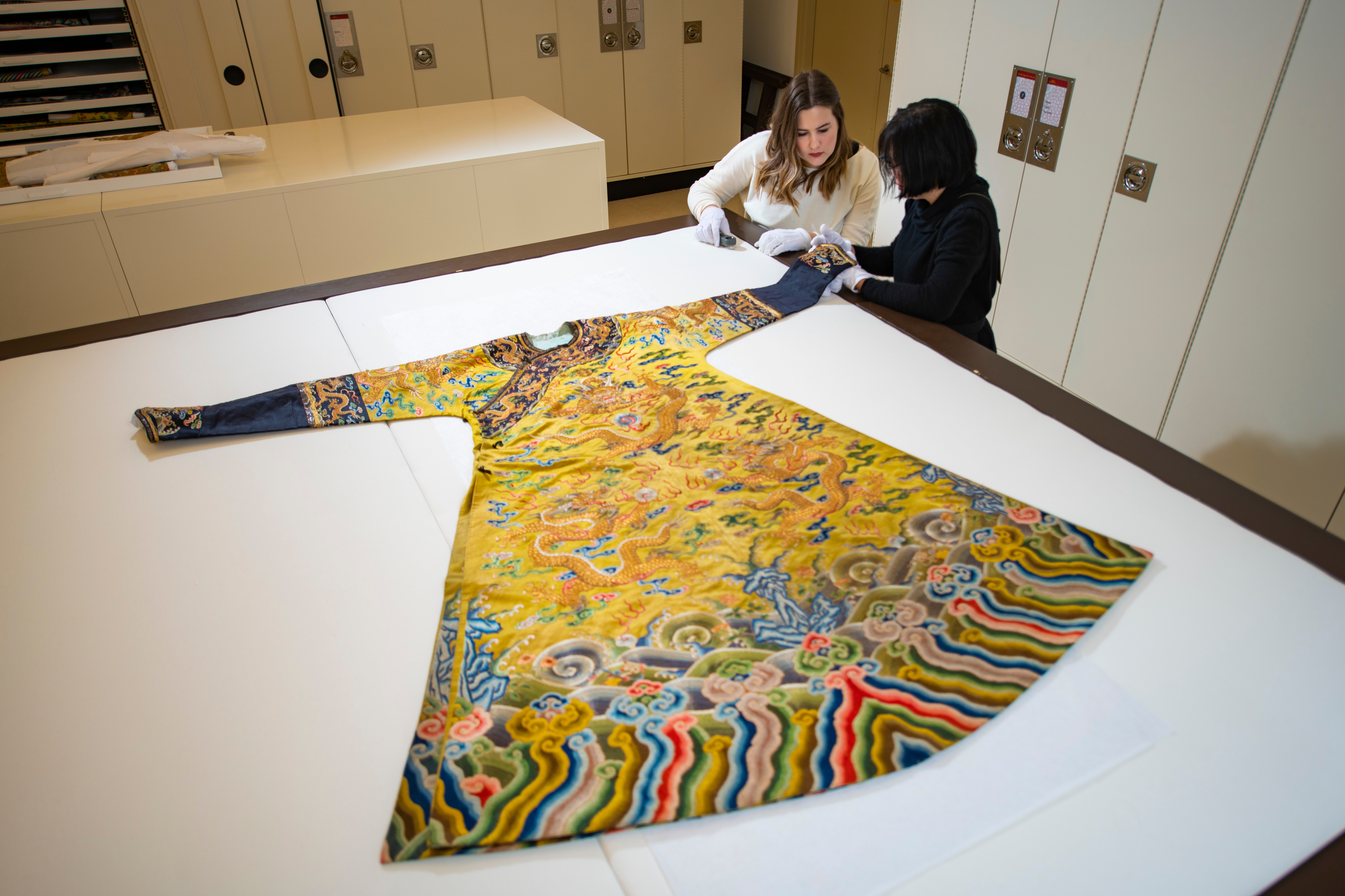 two UAM staff inspecting a Chinese robe