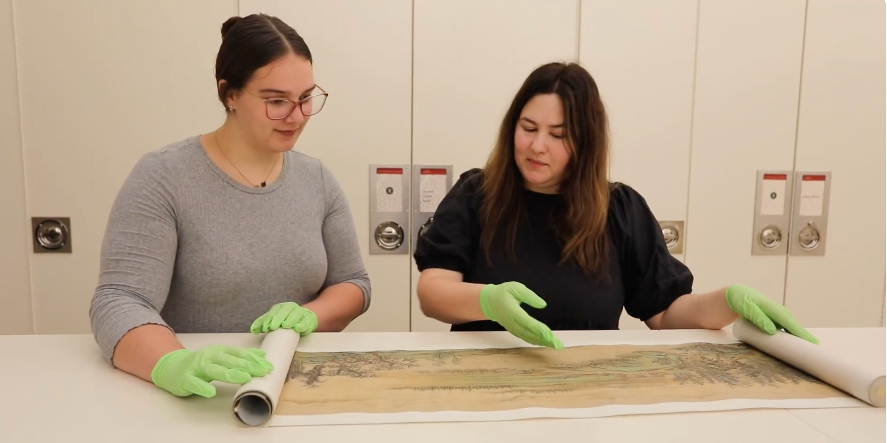 Two women looking at a hand scroll