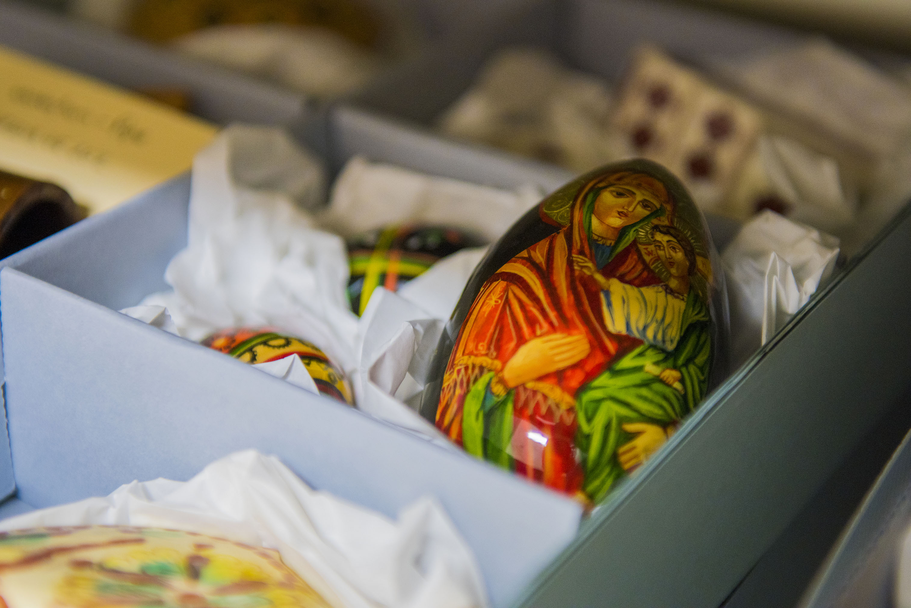A Ukrainian pysanky egg sitting upright in a small box surrounded by tissue, depicting the Virgin Mary