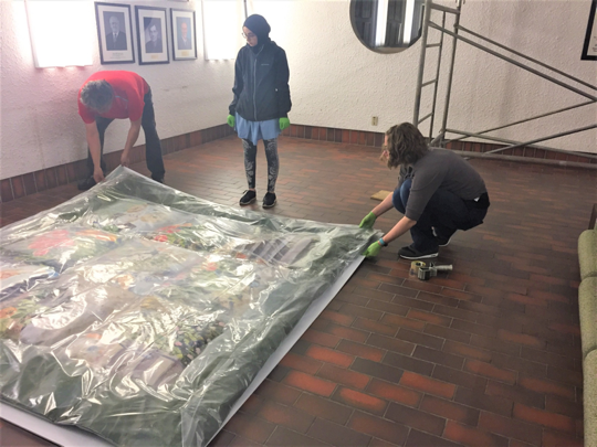 Fatme, Tom, and Jennifer protect the removed work of art for transport