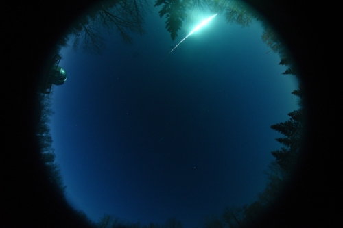 view of the night sky with a bright fireball flashing across the sky