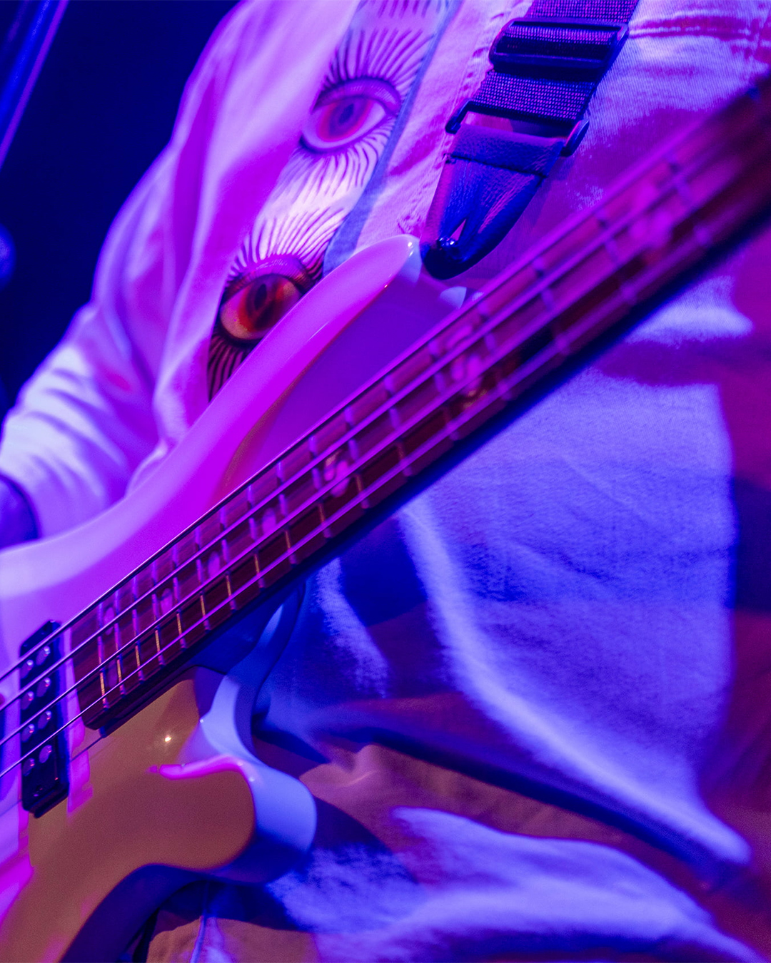 performer on stage laying electric bass under purple and blue lights. Photo from Getty Images