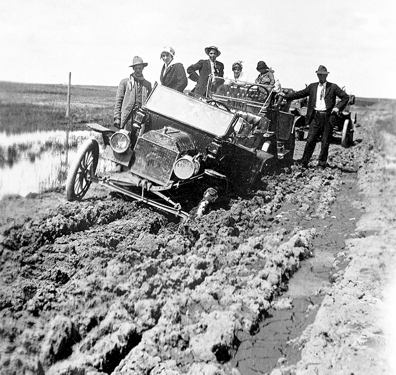 Archival photo of a car stuck on a muddy road near Hanna, Alberta, 1920s