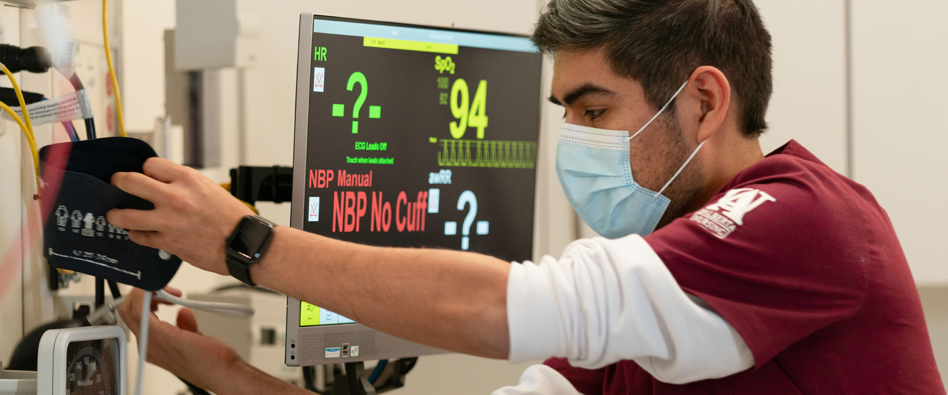 Male nursing student reaching for blood pressure sleeve
