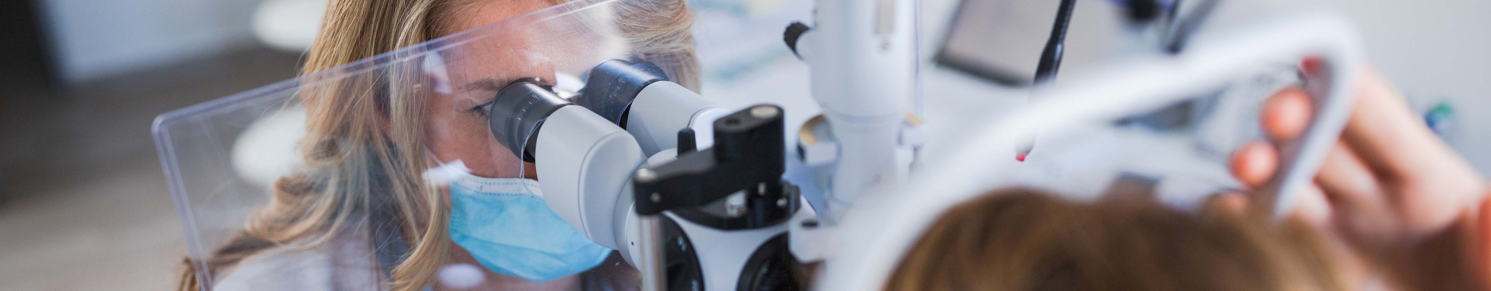 A healthcare professional conducts an eye examination using specialized optical equipment.