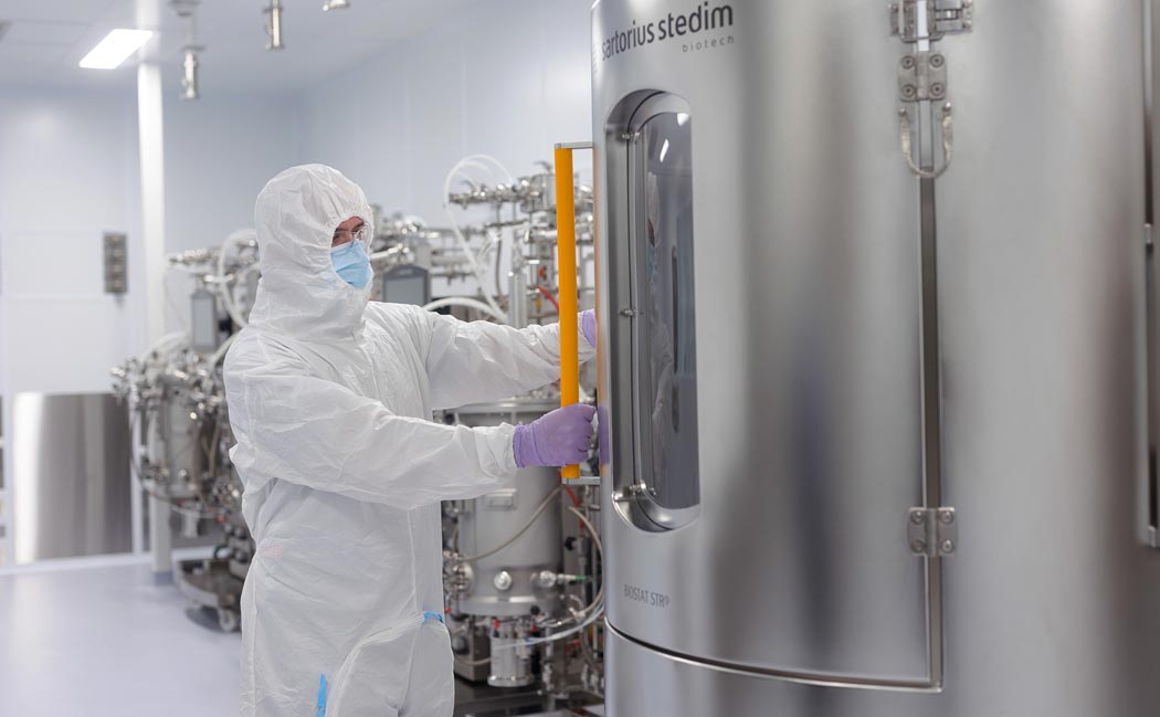 A researcher from Saskatchewan's Vaccine and Infectious Disease Organization (VIDO) wearing full protective equipment opening a bioreactor