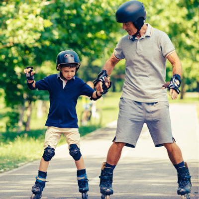 Child and father roller blading with protective gear
