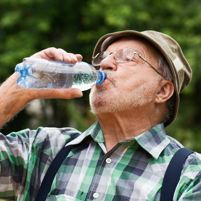Elderly man drinking water and wearing a hat.