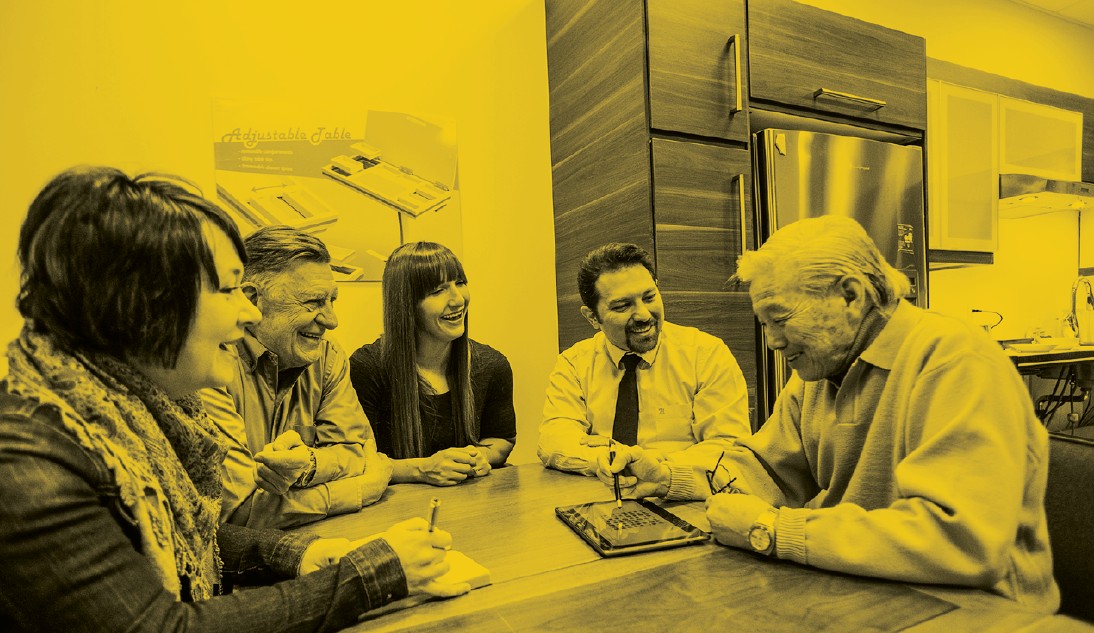 Five people sitting in a kitchen having a conversation