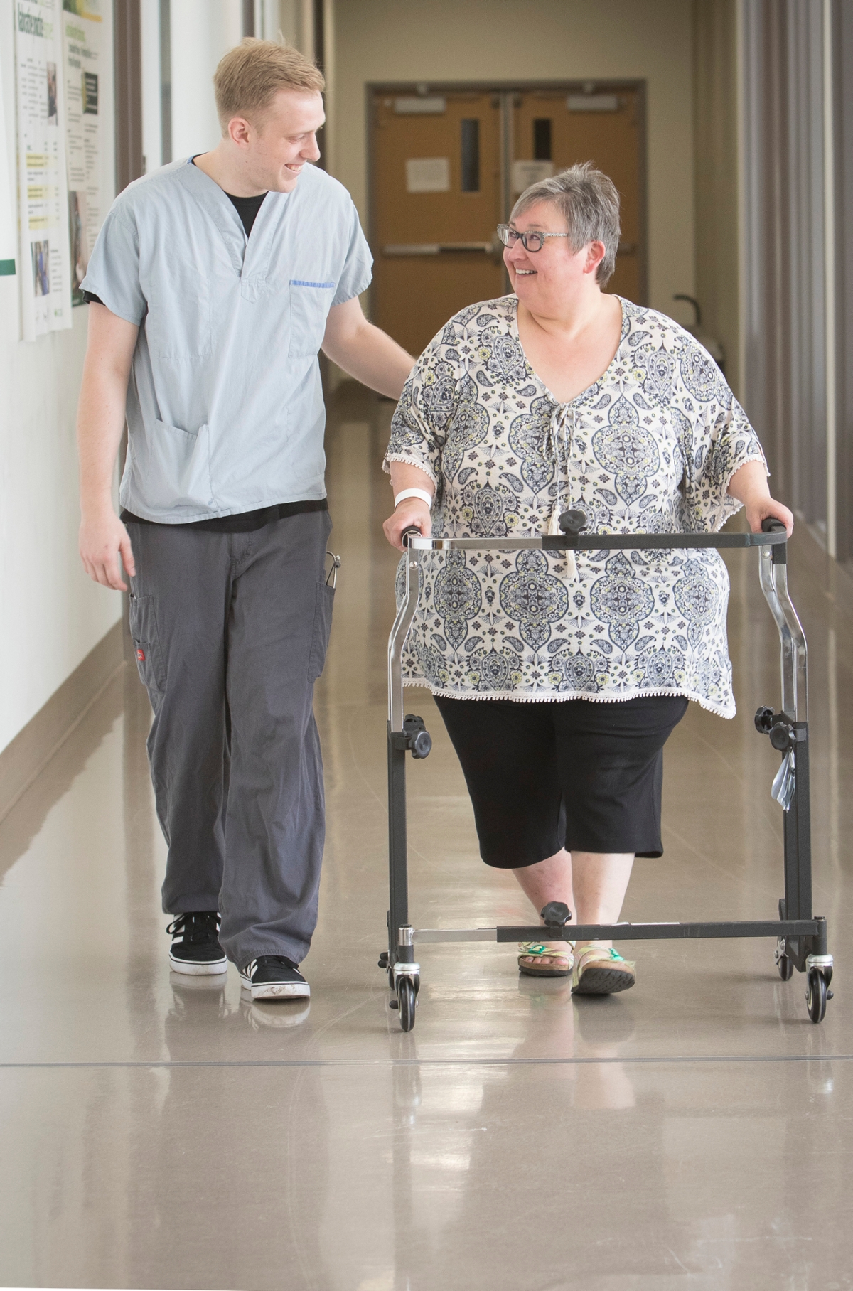clinician and obese patient with walker in hospital corridor