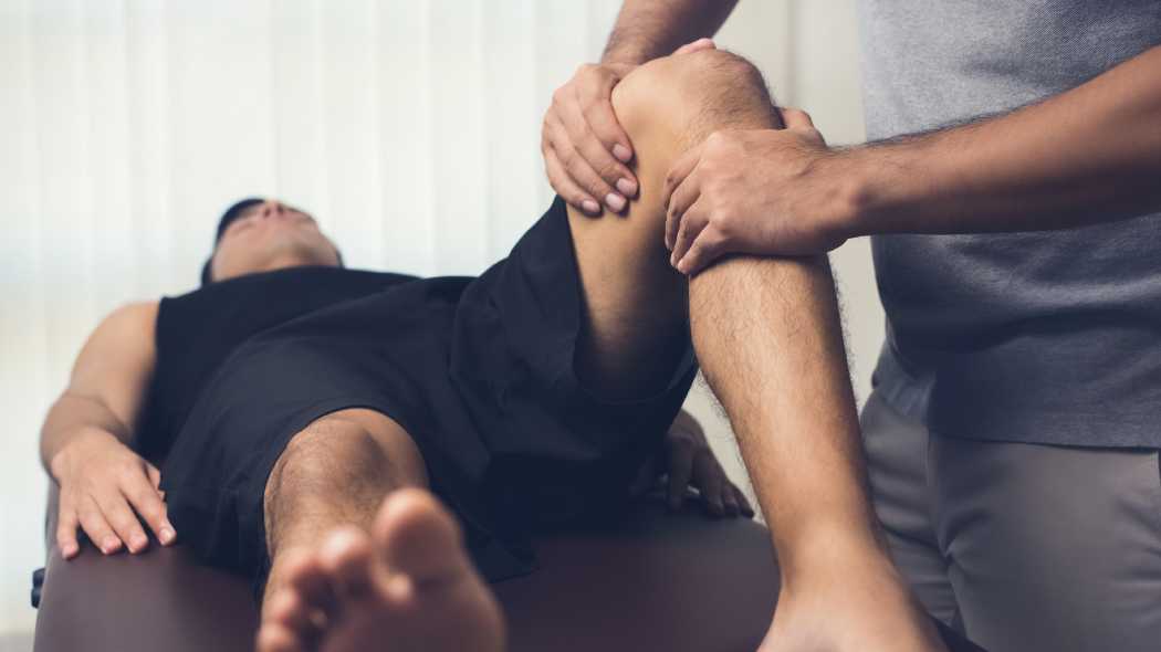 Man laying on doctor table getting his knee looked at