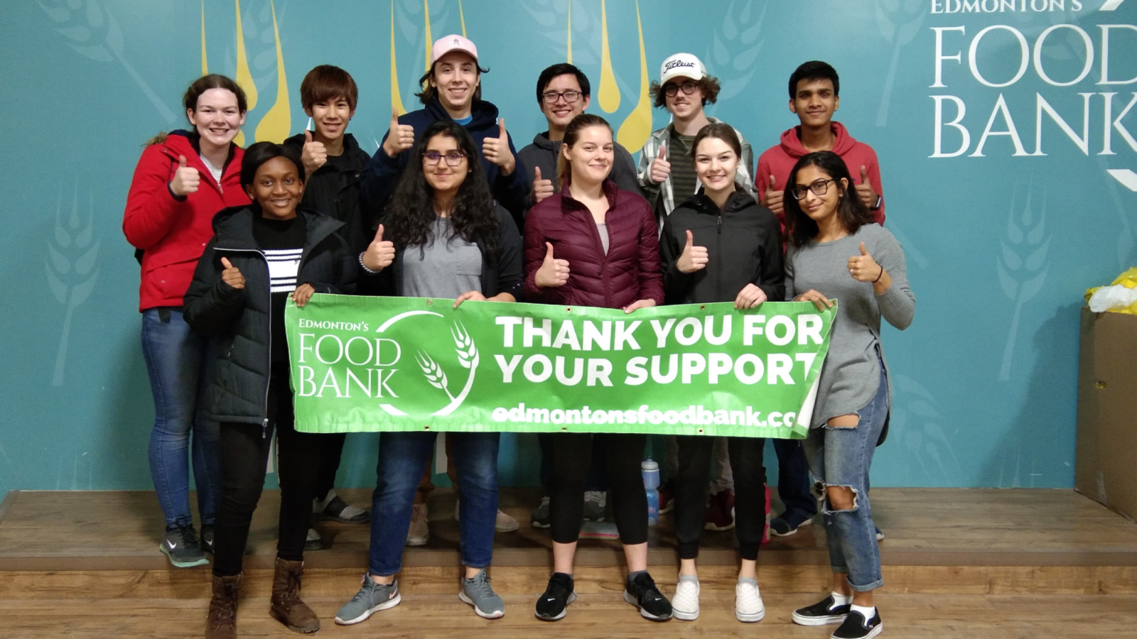 A group of volunteers stand behind a food bank banner.