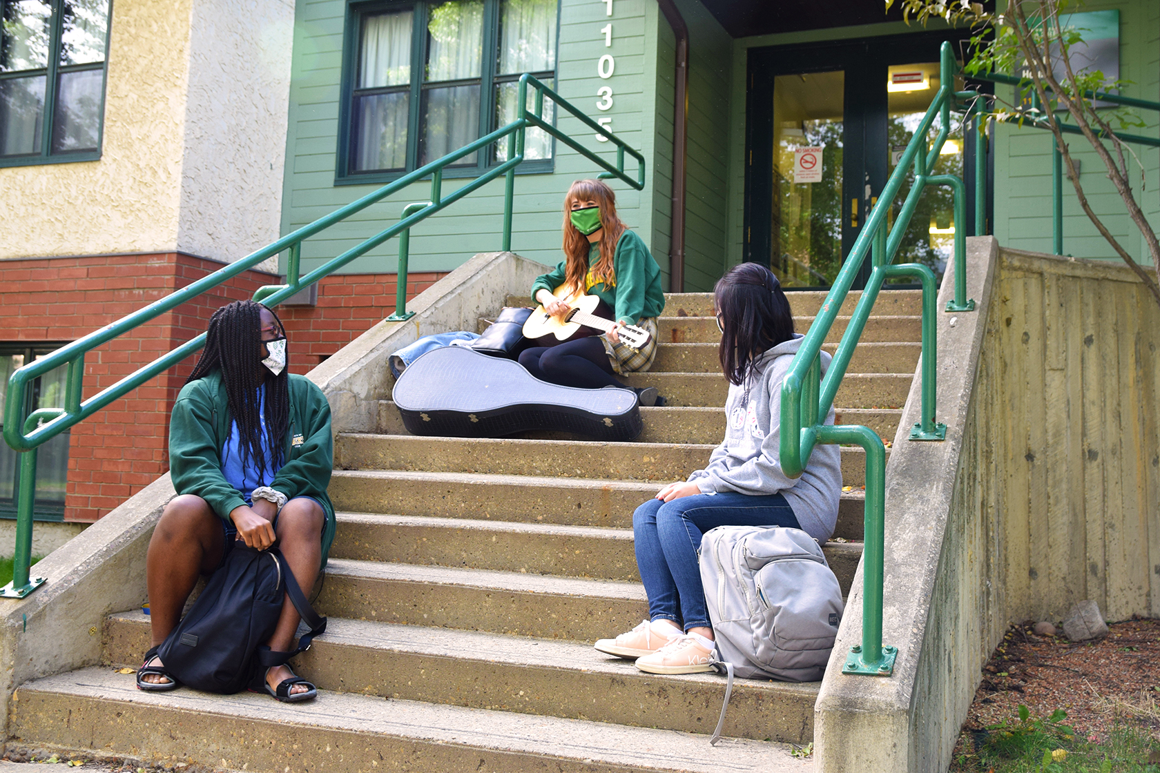 Student sitting on the steps of a UAlberta Residence during COVID
