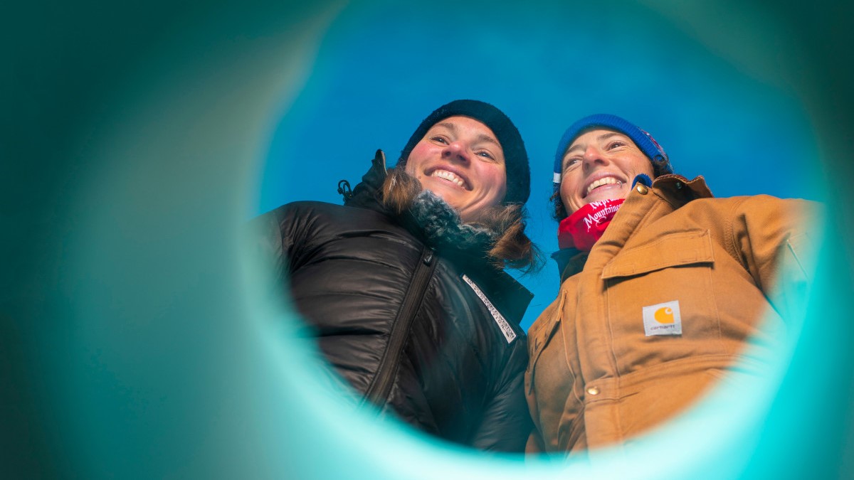 Ashley Dubnick, postdoctoral fellow at UAlberta in the Department of Earth and Atmospheric Sciences, and Alison Criscitiello, Director of the Canadian Ice Core Lab smiling through an ice core tube.