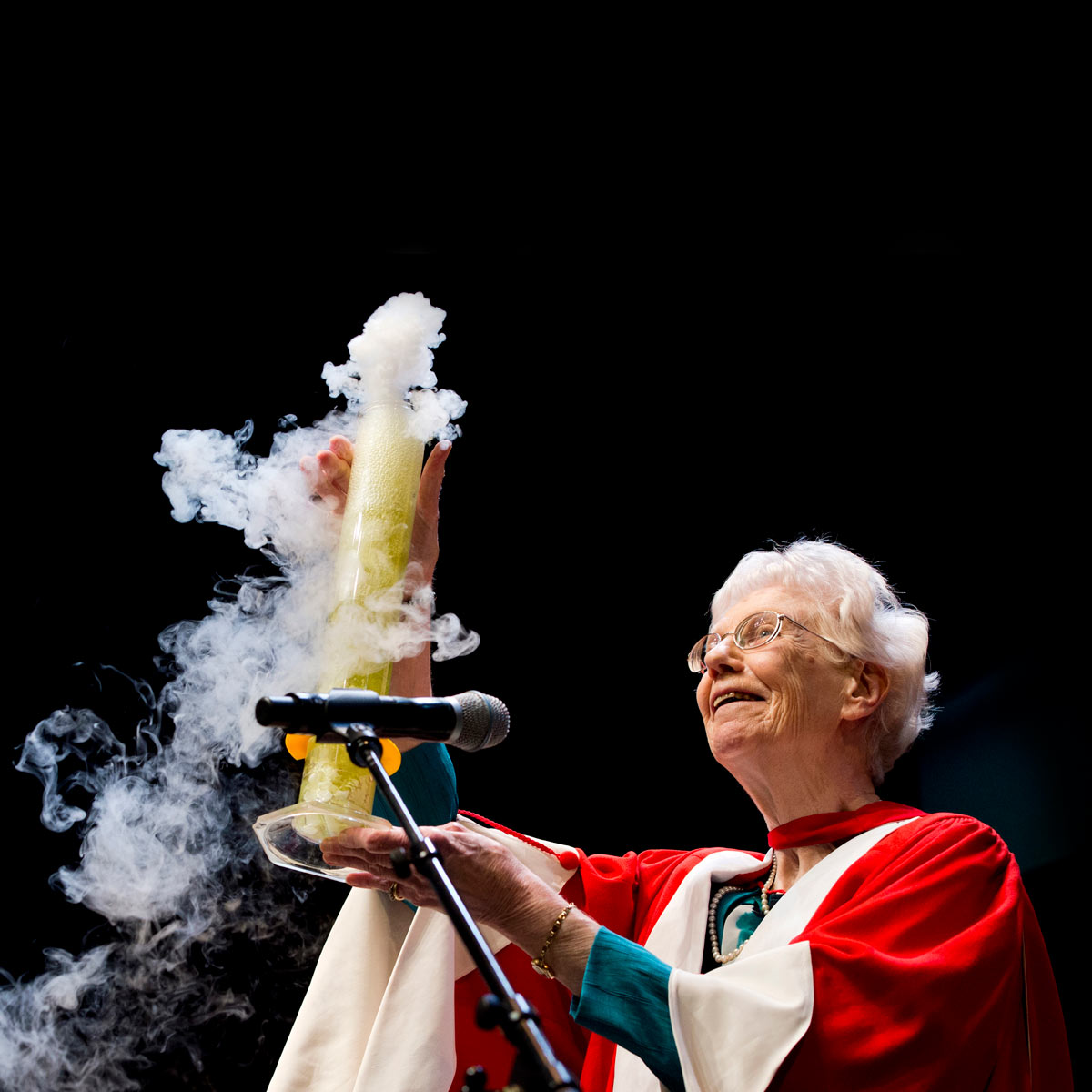 Dr. Margaret-Ann Armour during her Convocation address, holding aloft a large smoking beaker.