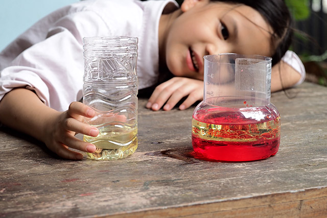 Child making oil and water separator experiment at home.
