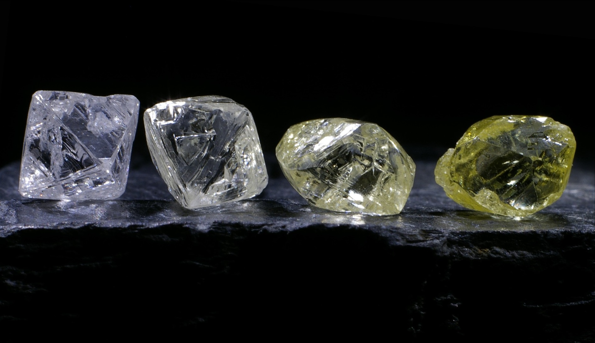 Four diamonds arranged in a row by colour, from colourless to yellow