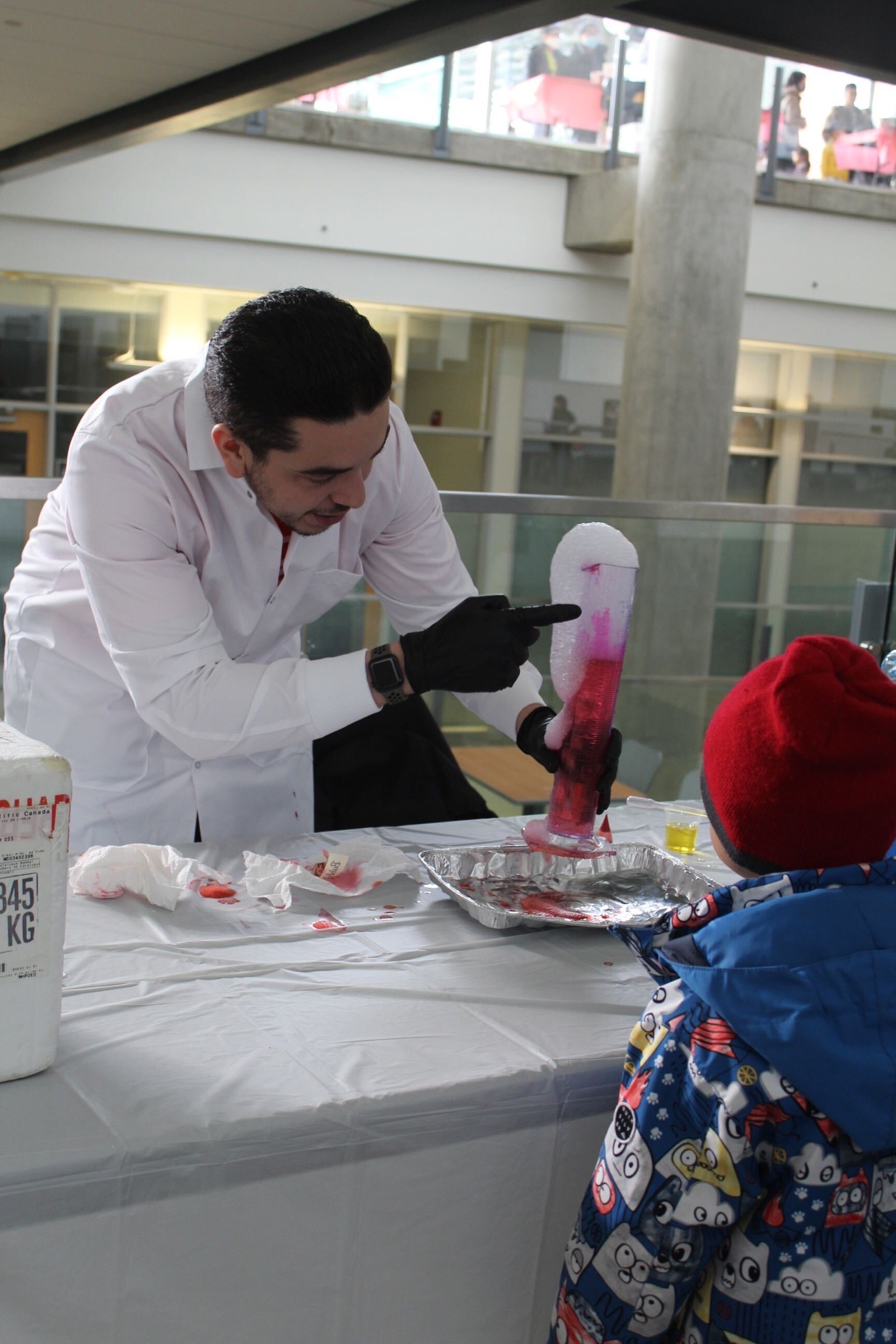A FUNday volunteer demonstrates bubbles forming from dry ice to an attentive crowd of children.