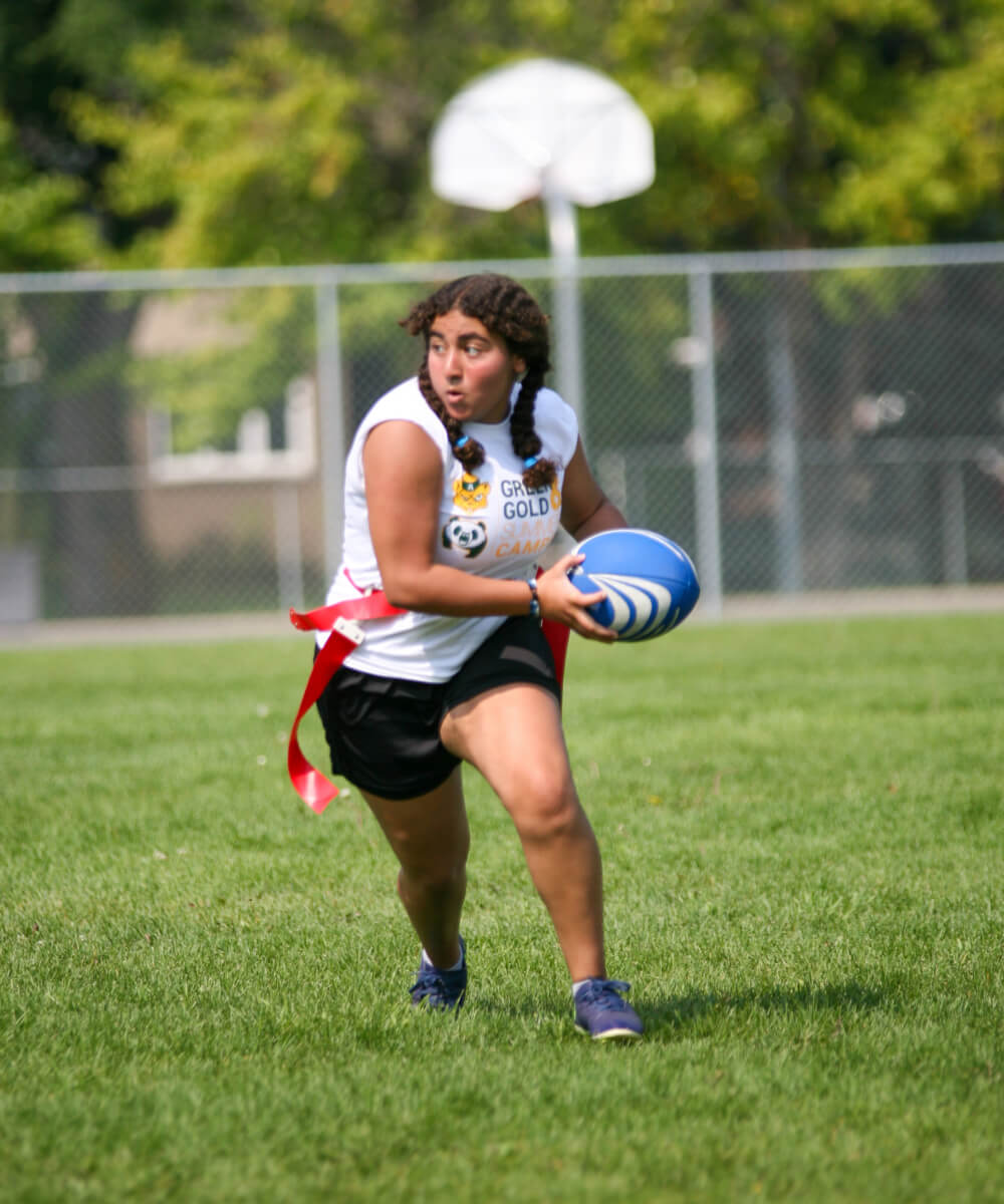 Green + Gold summer camp participant playing flag rugby