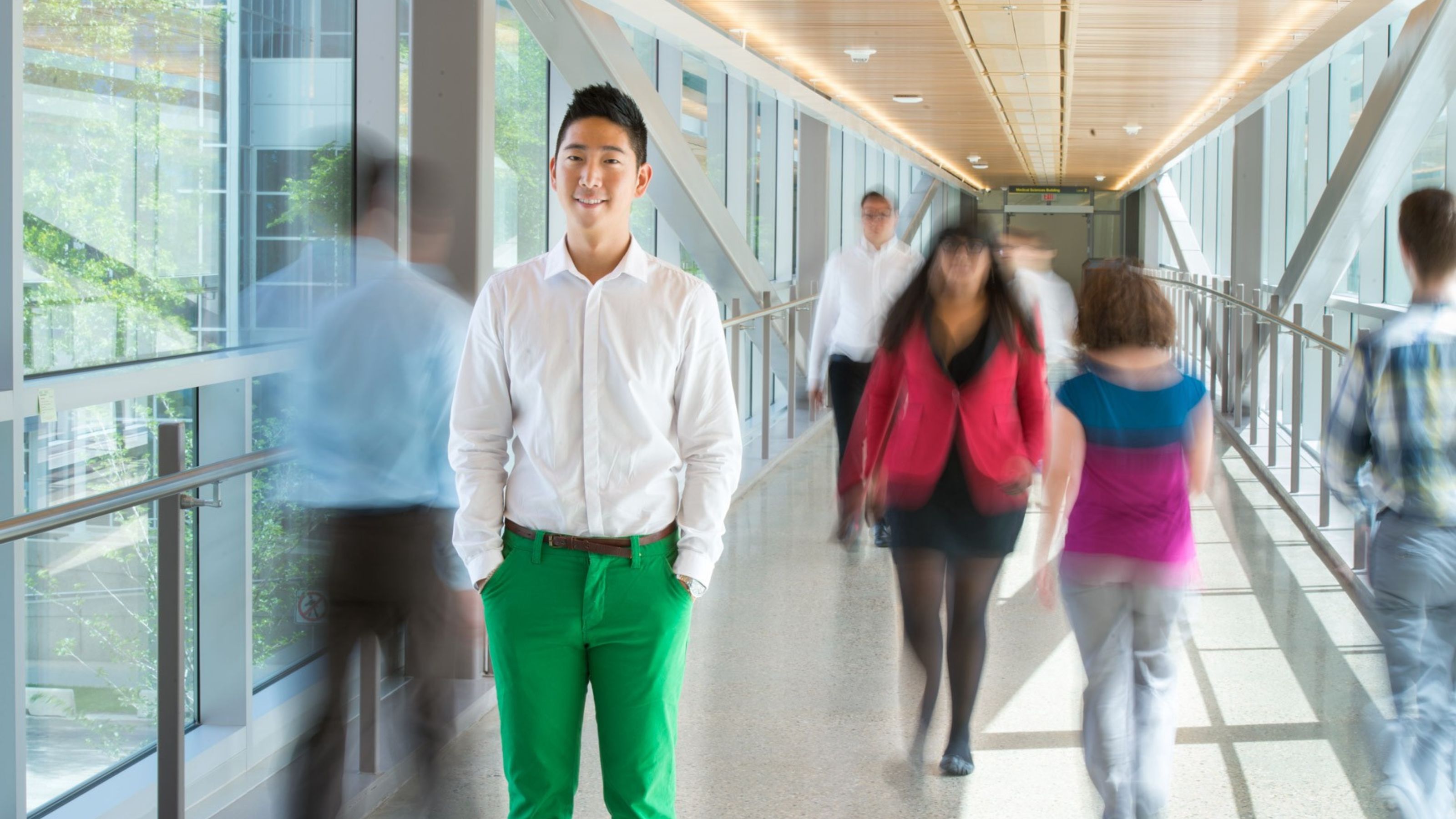 A student stands among a number of blurred individuals